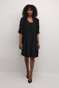 Vestido negro con escote en V, con mangas de encaje abullonadas. Tela suave, forma de línea A, longitud hasta la rodilla, combinado con tacones negros de punta.