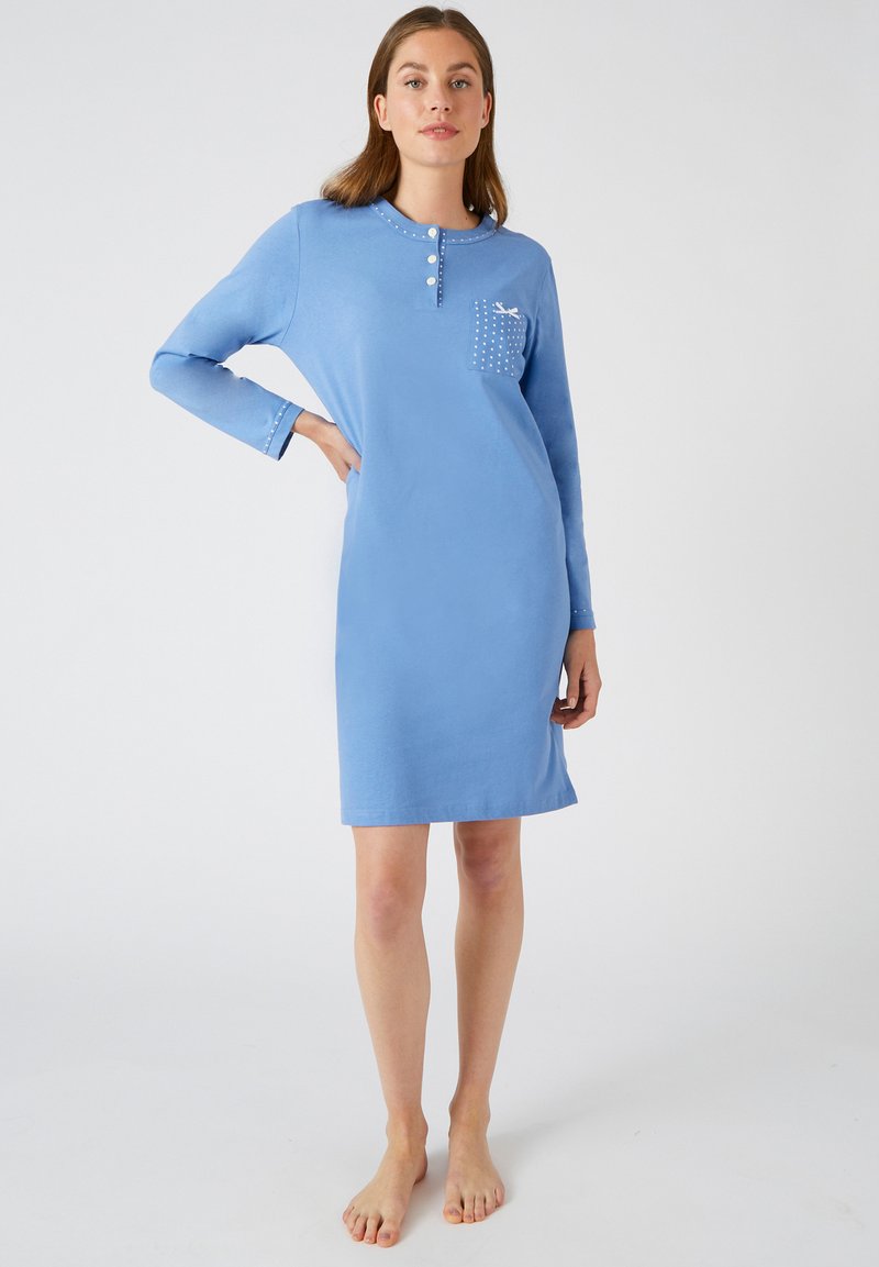 Robe en coton bleu clair avec des manches longues, un col rond, des boutons sur le devant et une poche poitrine ornée de motifs à pois blancs. Texture lisse.