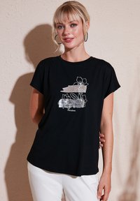 Sort T-shirt med korte ærmer, prydet med et sølvfarvet blomsterdesign og den tekstlige del "Floraison." Blødt bomuldsstof, afslappet pasform.
