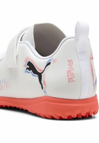 Valge sportlik king, millel on tekstureeritud oranž tallas, must Puma logo ja värvilised aktsendid. Kleebisrihm kindla kinnituse tagamiseks.