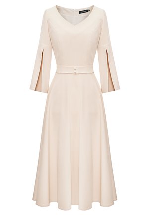 Jasno brzoskwiniowa sukienka z dekoltem w serek, rękawami trzy czwarte w kształcie dzwonu, dopasowaną talią z paskiem i guzikami oraz zwiewnym spódnicą do kolan. Gładka faktura.