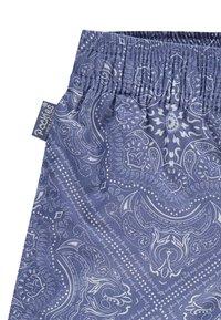 Mėlynos raštuotos trumpikės su elastine juosta, puikuojančios sudėtingais baltais paisley raštais ir mažėle prekės ženklo etikete. Lygi audinio tekstūra.