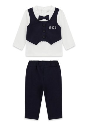 Completo formale per bambini con maglietta bianca a maniche lunghe, gilet blu navy e papillon, e pantaloni blu navy abbinati, con logo "GUESS" sul gilet.