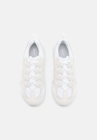 White athletic shoes featuring mesh and suede materials, with a grey Nike logo and contrasting white laces and midsole. Rounded shape.