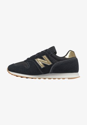 Baskets New Balance noires et dorées avec empeigne en daim et mesh, semelle intermédiaire blanche et semelle extérieure en gomme, vues de l'extérieur.
