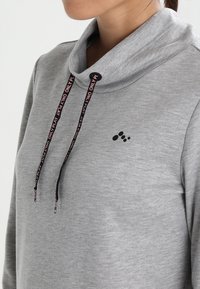 Sweat-shirt gris à col bénitier, avec des accents de logo noirs et des cordons ornés du texte "ONLY PLAY" en rose. Texture de tissu lisse.