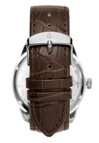 Brun lærreim med teksturert krokodillemønster, sølvfarget metallspenne, og stingdetaljer; fokus på reimens form og hardware.