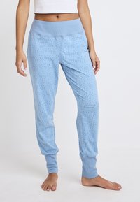 Lichtblauwe pyjamabroek met een gladde textuur, geribbelde tailleband en taps toelopende boorden, voorzien van een subtiel stippenpatroon.