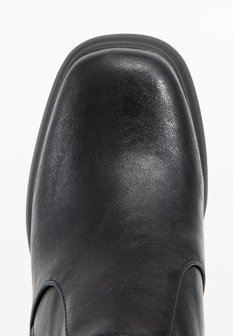 Chaussure en cuir noir avec un bout carré arrondi et une texture lisse, présentée en vue de dessus sur un fond blanc.