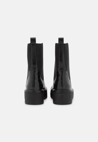 Bottines noires avec un corps en cuir lisse, des détails en cuir gaufré crocodile, des panneaux élastiques sur les côtés et une semelle épaisse.