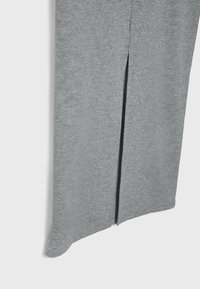 Jupe grise côtelée avec une fente latérale, une texture lisse et un ourlet régulier. Le tissu est léger et légèrement extensible.