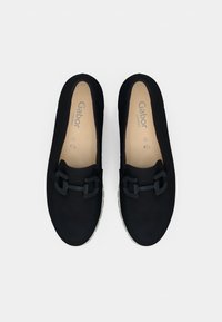 Μαύρα καθημερινά παπούτσια με δύο διακοσμητικές αγκράφες, κατασκευασμένα από μαλακό υλικό, με στρογγυλή μυτερή μύτη και υφασμένο πέλμα για καλύτερη πρόσφυση.