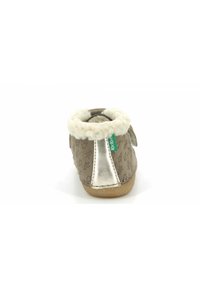Bota de ante marrón con un acento plateado, cuello de felpa blanca y patrones de bosque en relieve. Cierre con velcro para facilitar su uso.