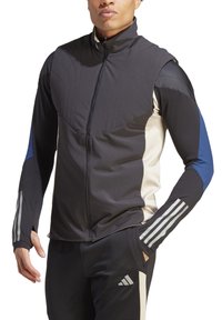 Chaqueta deportiva negra con un cuello alto, que presenta acentos en azul y beige, cierre de cremallera y paneles texturizados en el frente y las mangas.