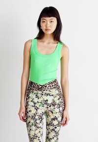 Groen aansluitend tanktop met een ronde hals, gecombineerd met hoge taille leggings met een bloemen- en luipaardprint.