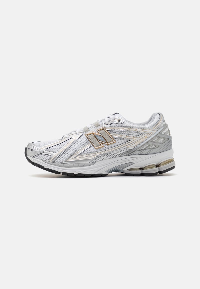 Chaussure de sport blanche et grise avec des panneaux en mesh, semelle amortissante, fermeture à lacets et logo New Balance sur le côté, montrée de profil.