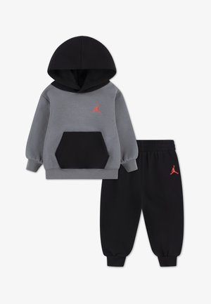 Set composto da felpa con cappuccio e pantaloni in pile grigio e nero, con tasca frontale e dettagli del logo rosso sulla felpa e sui pantaloni.