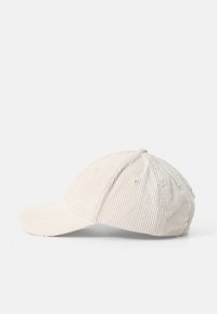 Beige corduroy cap with a curved visor, six ventilation eyelets, and a textured surface. Adjustable strap at the back for fit.