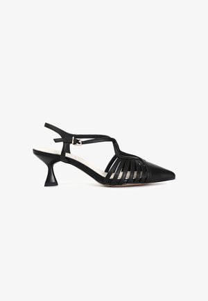 Czarne skórzane buty typu slingback z ostrym noskiem, z pionowymi wycięciami w paskach i sculpted obcasem w kształcie kociaka. Regulowany pasek wokół kostki.