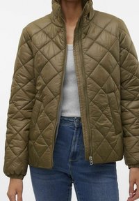 Chaqueta acolchada de color verde oliva con cuello alto y cierre de cremallera. Presenta puños elásticos y una tela suave y texturizada.