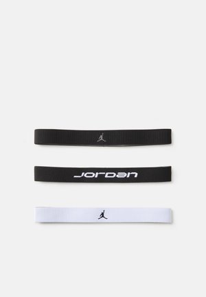 Conjunto de três elásticos para cabelo: preto com logótipo, preto com o texto "Jordan" e branco com logótipo. Textura suave, design estriado nos elásticos pretos.
