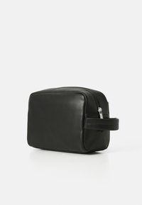 Borsa rettangolare in pelle nera con una superficie liscia, chiusura con zip e una maniglia laterale. Caratterizzata da un design minimalista e linee pulite.