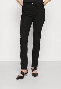 Svarta skinny jeans i denim med medelhög midja, slim fit och femfickorsdesign. Matchas med spetsiga svarta klackar.