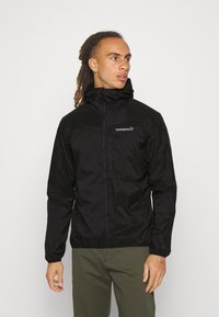 Black waterproof jacket with a high collar, zip closure, and logo detail on chest; features elastic cuffs and a lightweight design.