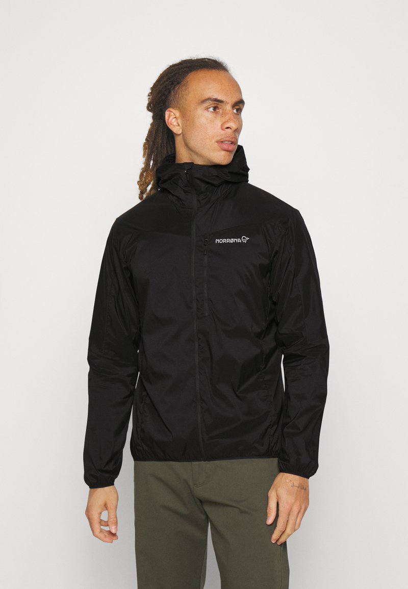 Black waterproof jacket with a high collar, zip closure, and logo detail on chest; features elastic cuffs and a lightweight design.