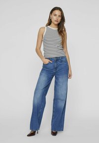 Rutet singlet topp kombinert med vide blå jeans. Jeansene har en avslappet passform, med en falmet vask og fem-lomme design.