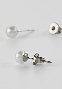 Hvite perleøredobber med bakstykke og stift i sølvfarget metall. Glatt, rund form med polert overflate; minimalistisk design.