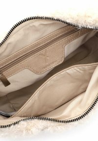 Borsa a tracolla beige con texture soffice, dotata di chiusura con zip e un interno liscio. La tasca interna è con zip, offrendo opzioni di stoccaggio.