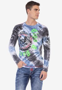 Langärmliges T-Shirt mit Batikdesign in Blau und Grau, ausgestattet mit schwarzen und neon-grünen Grafiken, einem runden Ausschnitt und einer taillierten Passform.