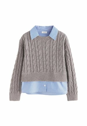 Szary krótki sweter z plecionym wzorem, nałożony na niebieską koszulę w paski z widocznym kołnierzykiem i mankietami.