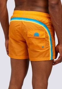 Pantaloni da bagno arancioni con una striscia blu, dotati di una tasca posteriore e di un patch con logo. Il tessuto ha una texture liscia e leggera.