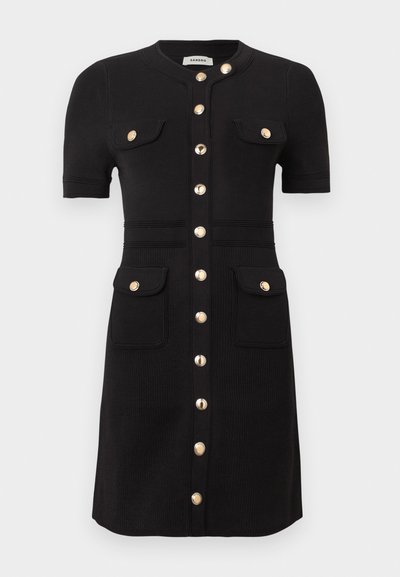 Robe noire à manches courtes avec encolure ronde, boutons dorés sur le devant, quatre poches à rabat avec boutons dorés, détail taille cintrée.