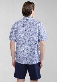 Korte mouwen overhemd met knopen, voorzien van een bloemenpatroon in blauw, wit en rood. Gemaakt van stof met een gladde textuur en een standaard kraag.
