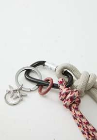 Keychain design featuring black and silver carabiners, pink and gray braided rope, and silver charms of two birds. Durable materials and textures.