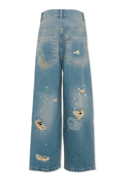 Jean large bleu clair à taille haute, avec des déchirures usées, des zones décolorées, deux poches arrière et de petits détails graphiques sur les jambes.