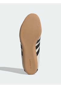 Sneaker sole in light brown rubber with a textured finish. Upper in white with three black stripes. Branding "adidas" embossed on the sole.