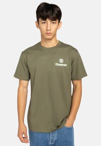 Olive zelené bavlnené tričko s klasickým round neckline a krátkymi rukávmi, s bielym logom potlačeným na ľavej strane hrudníka.