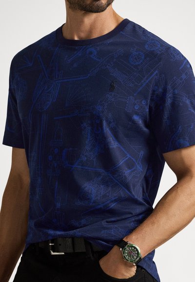 T-shirt azul-marinho de algodão, com um design gráfico de desenhos mecânicos. Decote canelado e um pequeno logótipo no peito.