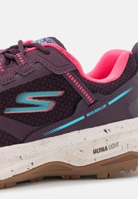 Paarse sportieve schoen met roze accenten, waterafstotend mesh bovenwerk, getextureerde buitenzool en "ULTRA LIGHT" branding op de middenzool.