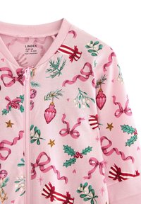 Pink zip-up jacket features a festive print of ornaments, ribbons, holly, and stars in various colors on a soft fabric background.