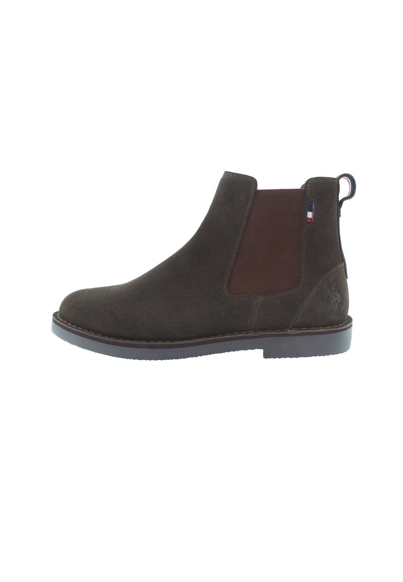 Bota Chelsea de ante marrón con paneles laterales elásticos y una lengüeta. Presenta una suela de goma lisa y costuras en contraste para un detalle adicional.