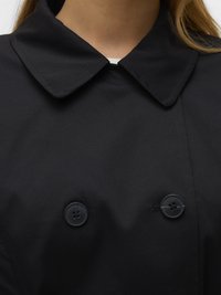 Manteau trench noir avec un large col, design à double boutonnage et deux boutons noirs visibles. Texture de tissu lisse, détails de couture minimaux.