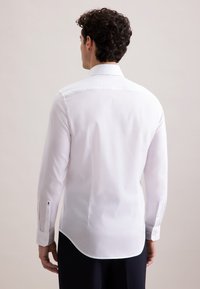 Witte langemouwen shirt met een klassieke kraag, gladde textuur, gebogen zoom, met knopen te sluiten manchetten en zijsplitten, bekeken vanaf de achterkant.