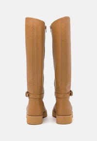 Bottes hautes en cuir bronzé à la texture lisse, avec des fermetures éclair à l'arrière et des sangles réglables autour de la cheville. Talons carrés solides.