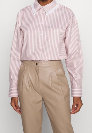 Camicia a maniche lunghe a righe rosa con colletto in pizzo bianco, dotata di chiusura con bottoni e una tasca sul petto.
