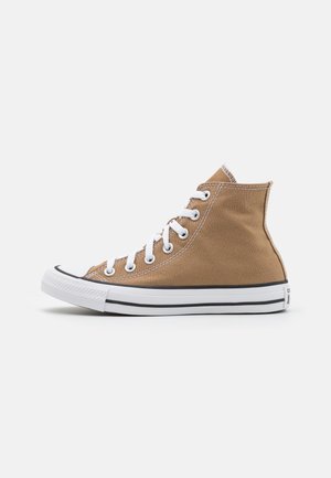 High-top canvas sneakers in a tan color with white laces and stitching. Features a rubber toe cap and black stripe detail on the sole.